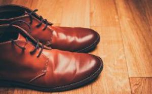Photographie d'une paire de souliers bruns sur un plancher de bois. La paire est placée de côté, sur la gauche.