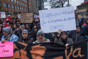 En avant plan, une femme tient une pancarte où il est inscrit occupez-vous de la santé, je m'occuperai de mon corps