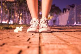 Photographie en gros plan sur les pieds d'une personne debout dans un milieu urbain.