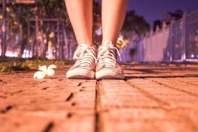 Photographie des pieds d'une personne debout dans la rue.