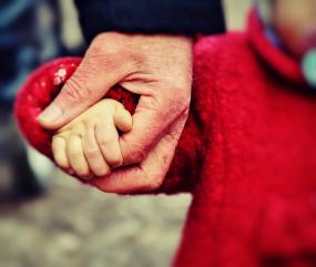 Photographie en gros plan sur les mains d'un enfant qui tient la main d'un adulte.