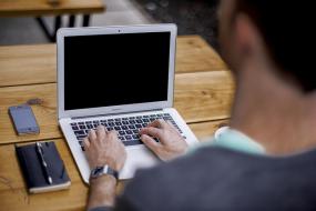 vue de dos d'un homme travaillant sur un ordinateur portable