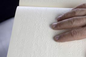 Photographie en gros plan d'une personne qui lit un livre en écriture Braille.