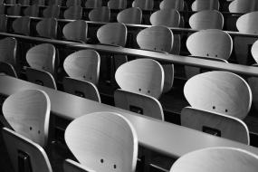 Photographie en noir et blanc de bancs vides dans un auditorium.