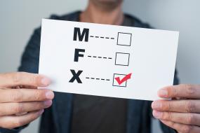 Photographie d'une personne tenant un carton avec les choix à cocher M, F et X. Le X est coché.