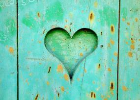 Photographie en gros plan d'une clôture turquoise. Au centre, un coeur est engravé.