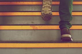 Photographie en gros plan sur les pieds d'une personne qui monte un escalier.