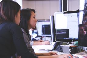 Photographie de profil de deux personnes travaillant à l'ordinateur.