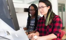 Photographie de deux femmes travaillant à l'ordinateur.