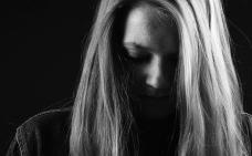 Photographie en noir et blanc d'une femme qui tient sa tête penchée vers l'avant.