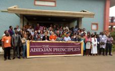 une foule devant un édifice tenant la banderole The Abidjan Principles