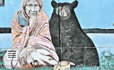 Art murale d'une femme autochtone assise à côté d'un ours noir.