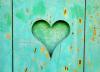 Photographie en gros plan d'une clôture turquoise. Au centre, un coeur est engravé.
