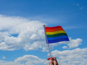 Drapeau de la fierté arc-en-ciel contre un ciel bleu avec des nuages.