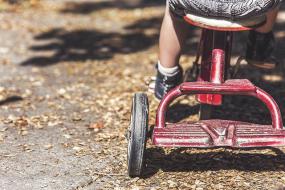 Photographie en gros plan d'un enfant sur un tricycle.