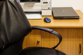 une chaise devant un bureau où se trouve une imprimante et un ordinateur portable