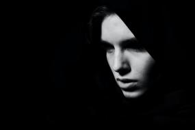 Photographie en noir et blanc sur fond noir du visage d'une personne.