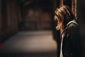 Photographie d'une jeune femme dans un corridor vide.