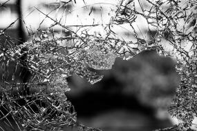 Photographie en noir et blanc d'une vitre brisée.
