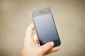 Photographie d'une main qui tient un téléphone portable.