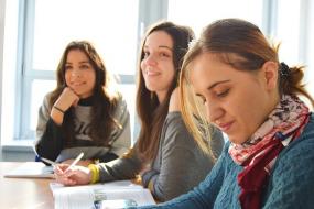 Photographie de trois étudiantes dans une salle de classe.