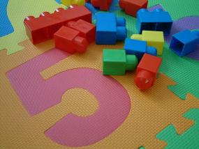 Photographie de blocs de construction sur un tapis coloré de type puzzle.