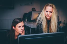 Photographie de deux femmes devant un ordinateur.