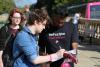 Une personne signe une feuille tenu par une personne portant un chandail HeForShe.